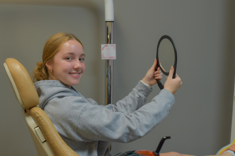 Orthodontist treating a young patient in the dental chair with an assistant nearby.
